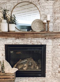 a fire place with a mirror and vases on the mantel above it in front of a brick fireplace