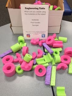 pink and green letters are on the table next to a box with writing in it