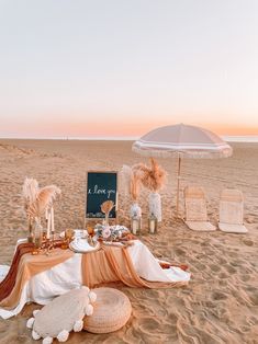 a table set up on the beach with an umbrella and other things to eat in it