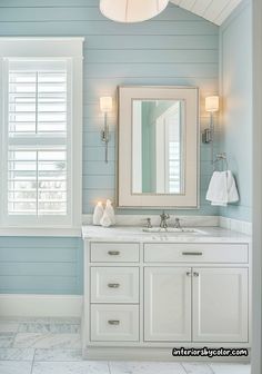 a bathroom with blue walls and white cabinetry has a large mirror above the sink