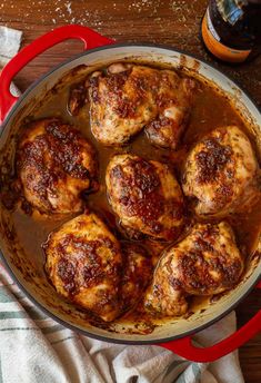 some meatballs are cooking in a pan on a table with a glass of wine