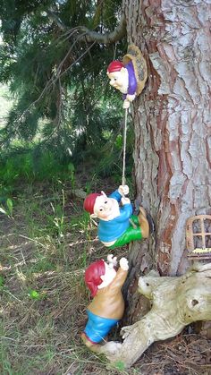 three figurines are hanging on the side of a tree