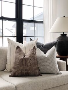 a couch with two pillows and a lamp in front of the window, next to it