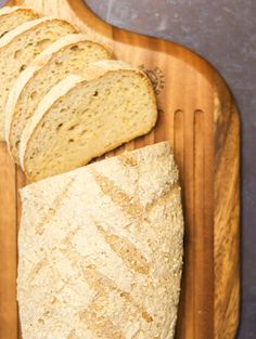 a loaf of bread sitting on top of a cutting board next to slices of bread