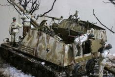 some toy soldiers are standing on top of a tank in the snow with trees and branches behind them