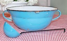 a blue bowl and spoon sitting on top of a checkered tablecloth with white flowers in the background