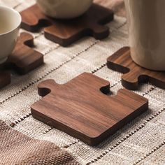 a wooden puzzle piece sitting on top of a table next to a cup and saucer