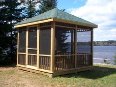 a gazebo sitting on top of a lush green field next to a body of water