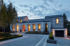 a large house with lots of windows and lights on it's front entrance at night