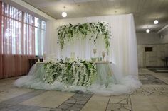 a table with flowers and candles on it in front of a curtained wall at a wedding reception