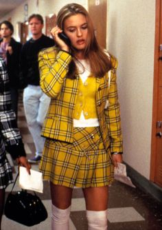 two women in plaid outfits talking on cell phones while others walk down the hallway behind them