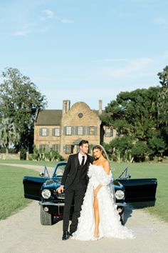 a bride and groom standing in front of an old car