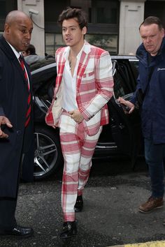 a man in a red and white suit is walking down the street with another man