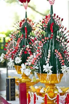 flowers are in gold vases with red candles on the table next to each other