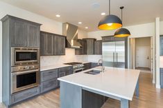 a large kitchen with stainless steel appliances and wood flooring is pictured in this image