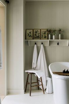 a white bath tub sitting next to a wooden shelf filled with towels and other items