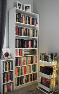 a book shelf filled with lots of books next to a window