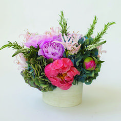 a white vase filled with lots of different colored flowers