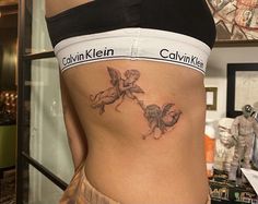 a woman with a tattoo on her stomach that has cupid cherubs on it