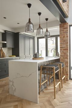 an image of a kitchen setting with bar stools in the foreground and large windows