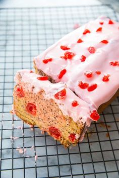 a piece of cake with white frosting and red candies on it sitting on a cooling rack