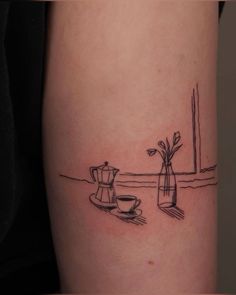 a black and white photo of a coffee pot with flowers on the side of a woman's leg