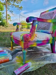 a chair that is sitting in the grass with some paint on it and several other items around it