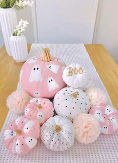 pink and white pumpkins are arranged on a table with pom - poms