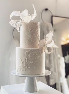 a three tiered white wedding cake sitting on top of a table in front of a mirror