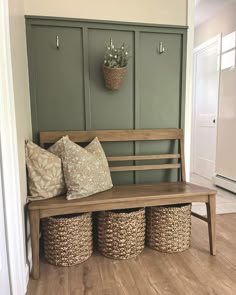 a wooden bench sitting next to two baskets on top of a hard wood floor in front of a green wall