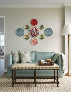 a living room with blue couches and plates on the wall above it's coffee table