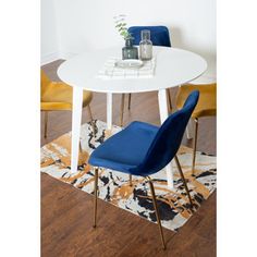 a white table with two blue chairs next to it on a brown and yellow rug