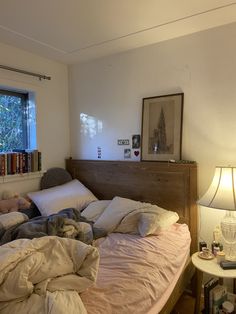 an unmade bed with pillows and blankets on it in front of a large window