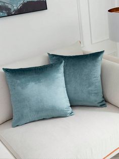 two teal pillows on a white couch