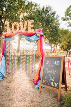 a sign that says love is in front of a decorated arch with ribbons and streamers