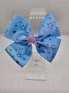 A cute sky-blue boutique bow with rainbow stars and an iridescent pink star charm! Made with polyester, blue printed grosgrain ribbon.  All my bows are hand-sewn. Measures approximately 4 inches x 3 inches and is on a 1.75-inch alligator clip. This bow is great for any time of the year when your little one wants to feel like a star!   It looks great in short or long hair! Hair bows make great accessory clips for scarves, purses, and flip-flops too! Makes a great gift or stocking stuffer! Oak Island Nc, Blue Boutique, Rainbow Stars, Rainbow Star, Pink Star, Oak Island, Boutique Bows, Making Hair Bows, Pink Stars