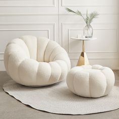 two white chairs and a table with a plant on it in a living room setting