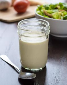 there is a bowl of salad and a glass of milk on the table next to it