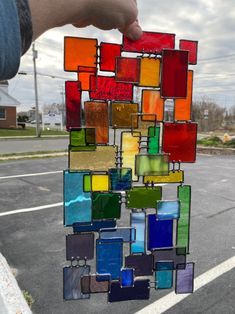 a person holding up a multicolored piece of art made out of stained glass