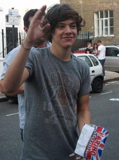 a young man making the peace sign while holding a box of chips in his hand