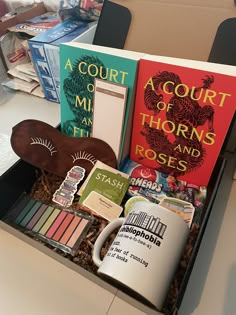 two books in a box with coffee mugs and other items sitting on the table