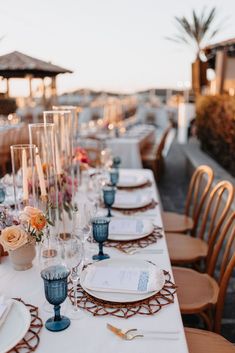 a long table set with place settings and candles