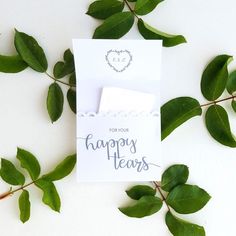 a white card with the words happy tears on it next to some green leafy branches