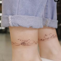 two people with matching tattoos on their legs, one has a wave and the other has a bird