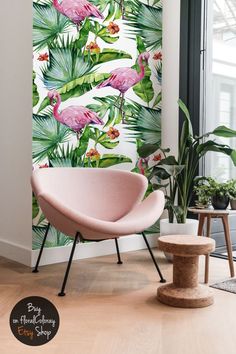 a pink chair sitting in front of a window next to a wall with flamingos on it