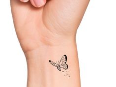 a woman's wrist with a small butterfly tattoo on the left side of her arm