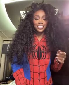 a woman with long curly hair wearing a spiderman shirt and holding a cell phone