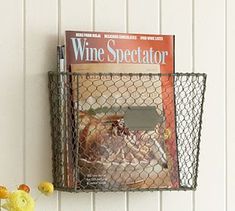 a magazine rack holding magazines on the wall next to a vase with flowers in it