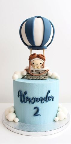 a blue and white birthday cake with a hot air balloon on it's top