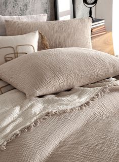 an unmade bed with several pillows and blankets on top of it in front of a clock